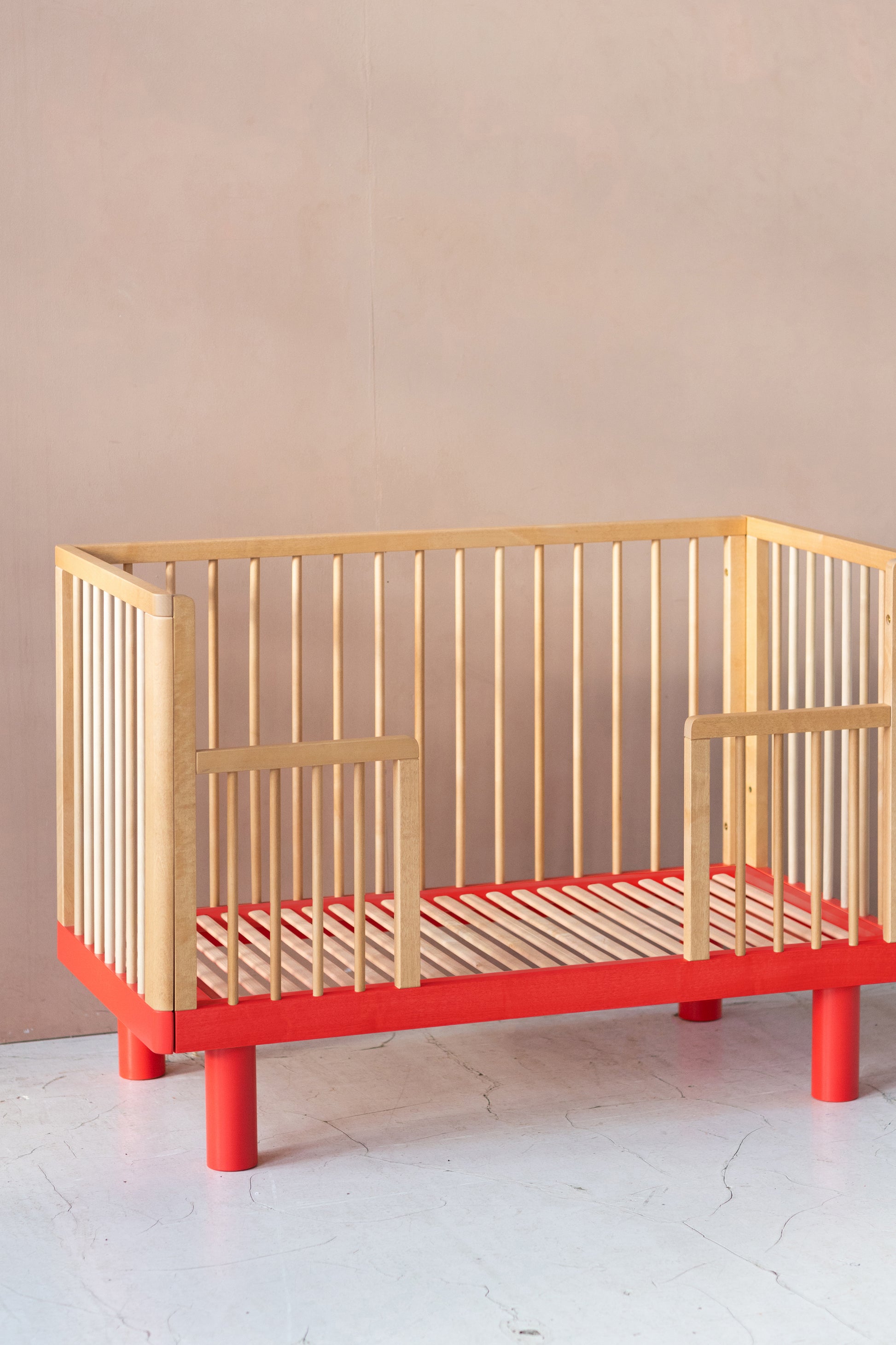 Nox cot in natural wood and red conversion rail in natural wood