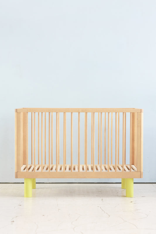 natural wood baby cot with yellow details