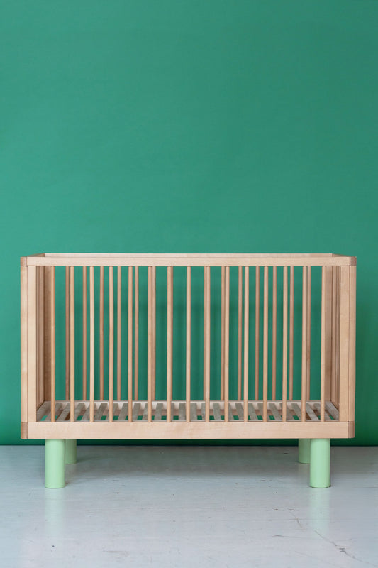 natural wood baby cot with green legs